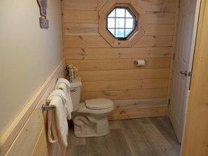 A small, wooden-paneled bathroom with a toilet, a towel rack, and a window. - Hot Tub, Lake View Cottage, Dog Friendly, Lake Access (Dundee)