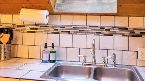 A kitchen with a skylight, a double sink, and a tiled backsplash.