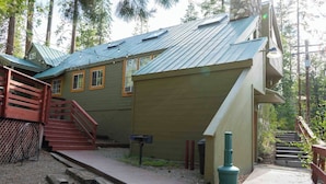 A cabin with a metal roof, wooden stairs, a mailbox, and a wooden deck.