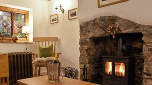 Ein gemütliches Wohnzimmer mit Kamin aus Stein, einem Holztisch, einem Sessel und einer Heizung.