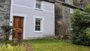 Ein Steinhaus mit weißer Fassade, einer Holztür und einem kleinen Fenster.