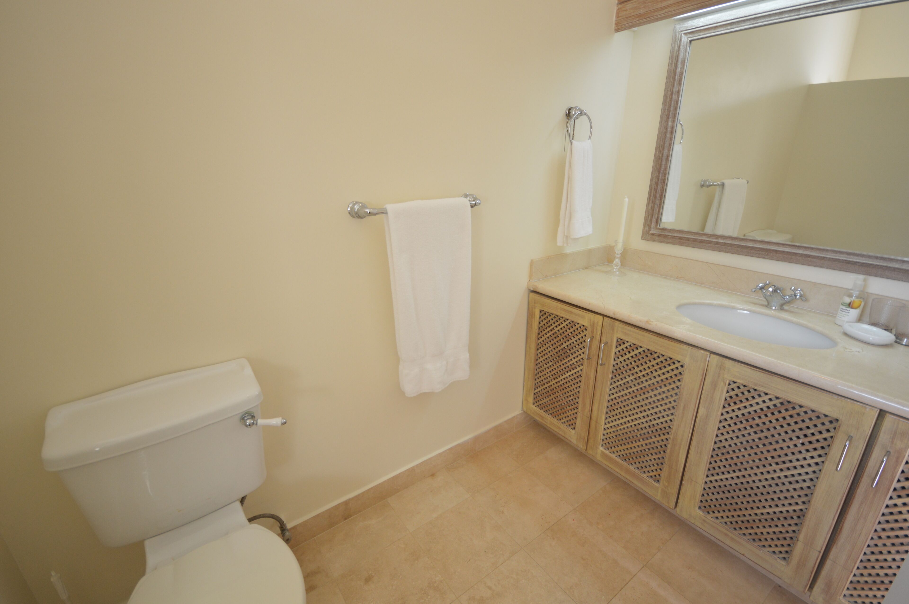 Une salle de bain comprenant des toilettes, un lavabo, un miroir et des placards.