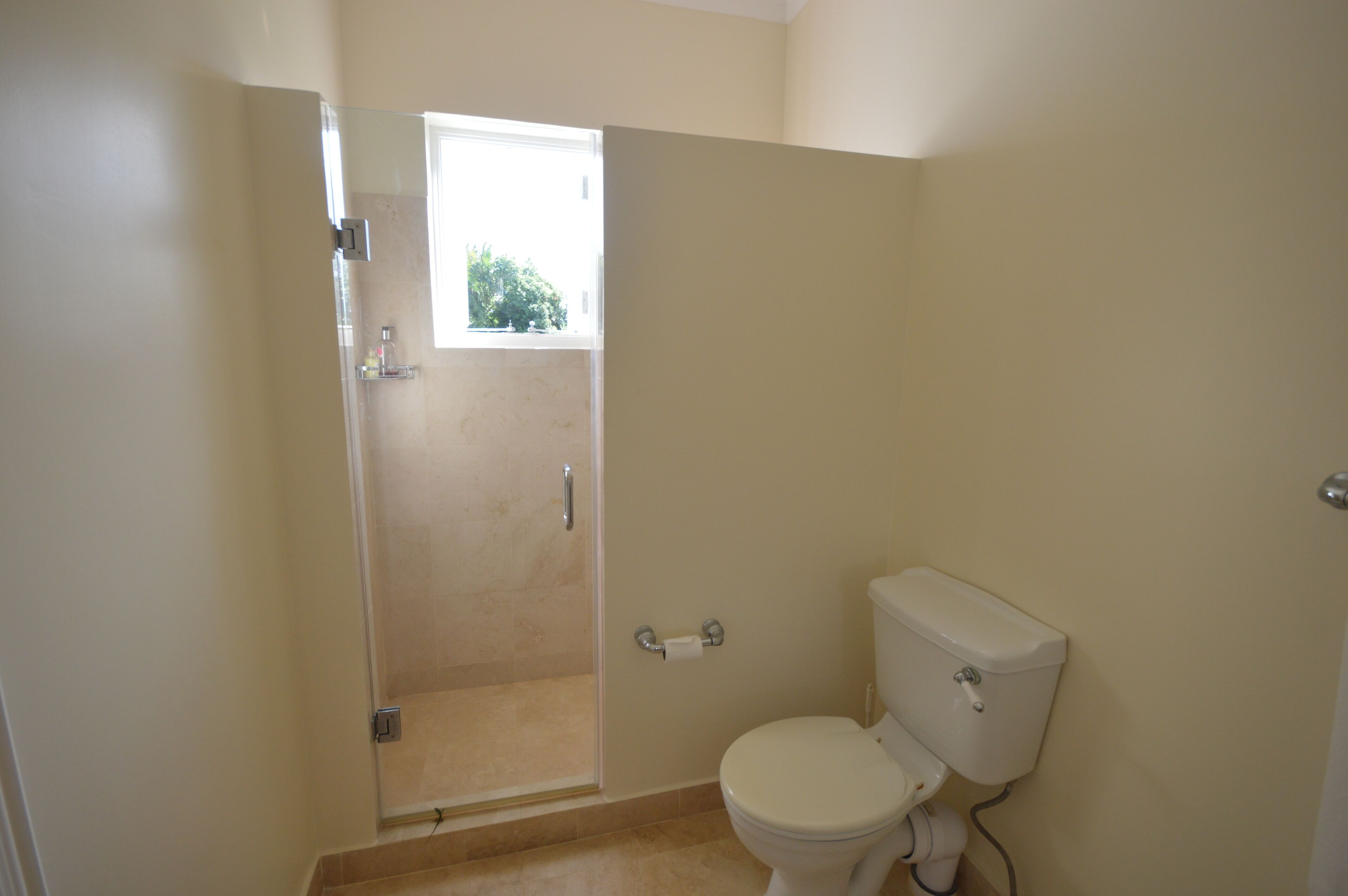 Ein Badezimmer mit Toilette, Dusche und Fenster.