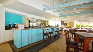 A bar area with a turquoise bar counter, wooden chairs, and ceiling fans. - The Garden Loft with pool and club house access (Mount Standfast, St. James)