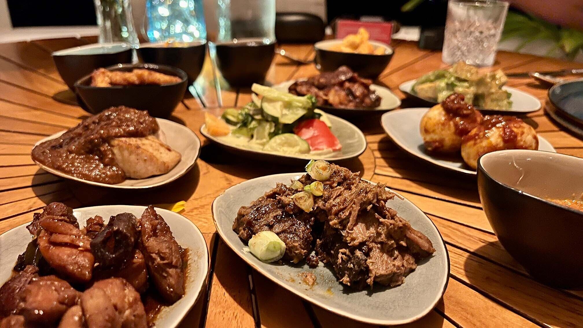 A table with various dishes including meat, vegetables, and a bowl of soup.