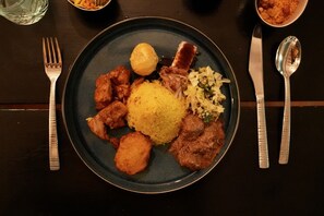 A plate of food with various dishes including rice, meat, and vegetables. -  Quill Gardens Boutique Hotel (Oranjestad)