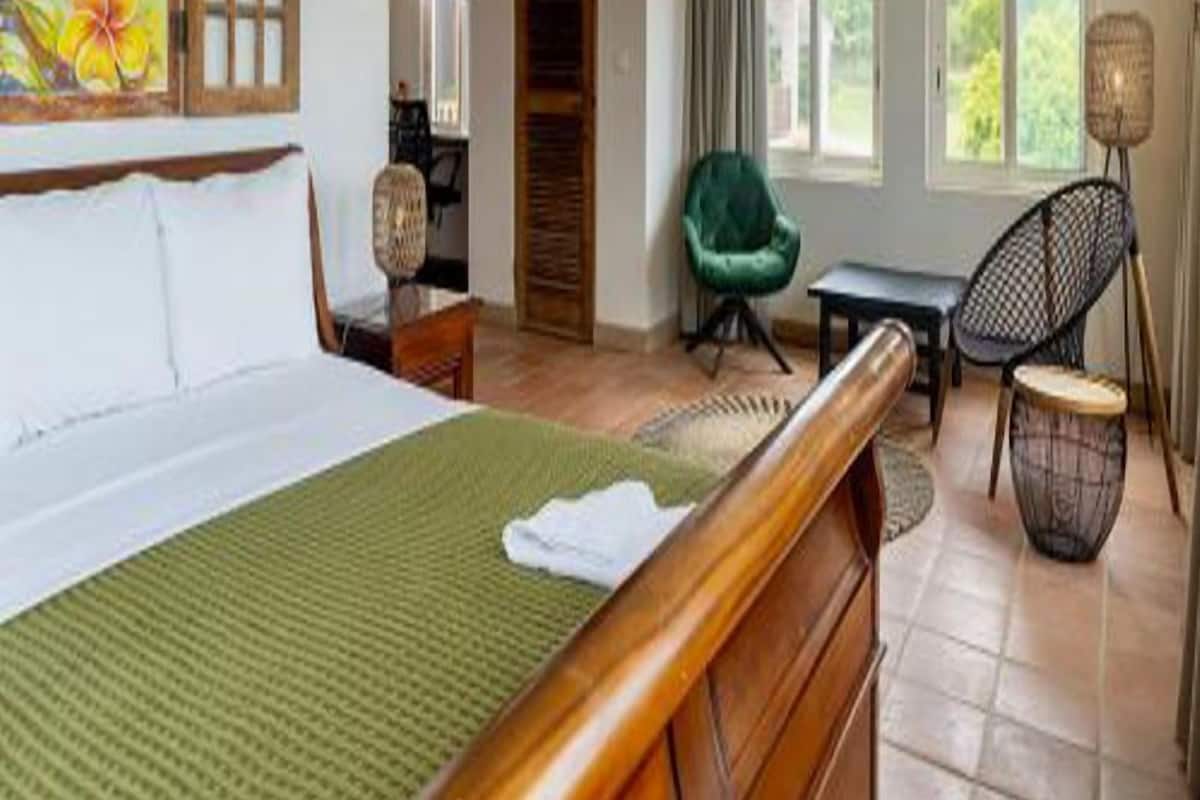 A hotel room with a bed, a desk, a chair, and a view of the outdoors.