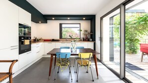 A modern kitchen with white cabinets, a wooden dining table, and two chairs. - La Coursive: beautiful luxury home with swimming pool (Montpellier)