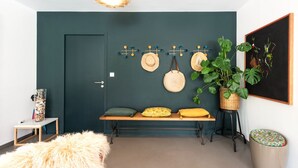 A room with a teal accent wall, a bench with cushions, a hanging hat rack, a large potted plant, and a framed abstract painting. - La Coursive: beautiful luxury home with swimming pool (Montpellier)