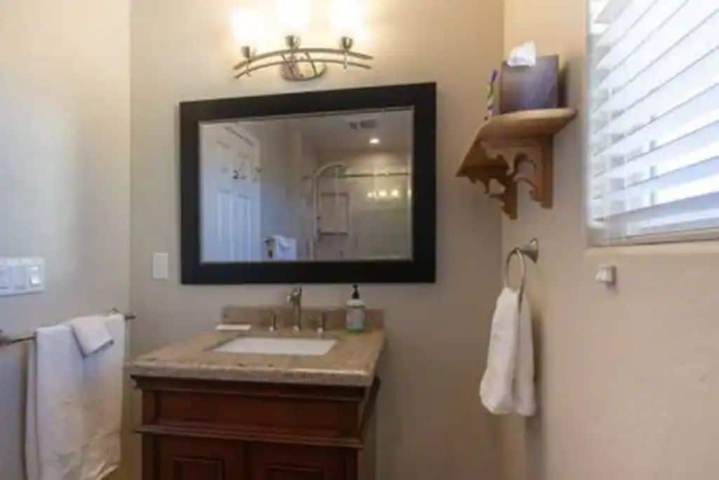 A bathroom with a wooden vanity, a large mirror, and a towel rack.
