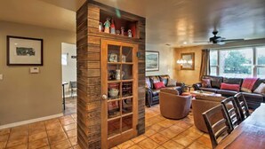 A spacious living room with a wooden cabinet, a dining area with a long table, and a cozy seating arrangement.