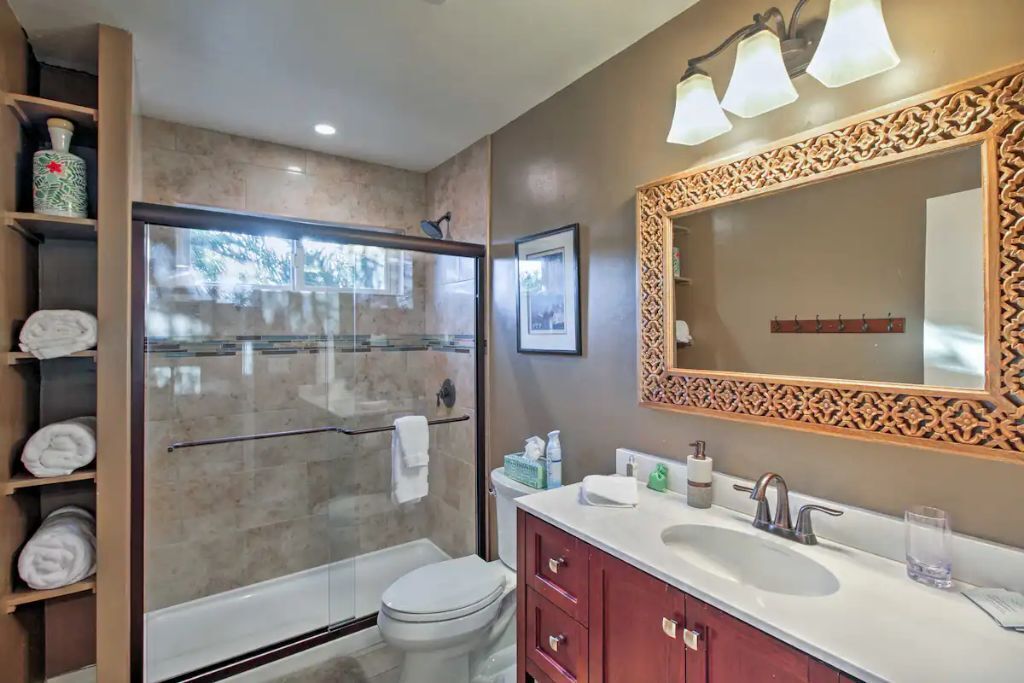 A modern bathroom with a glass-enclosed shower, a white toilet, a vanity with a mirror, and a towel rack.