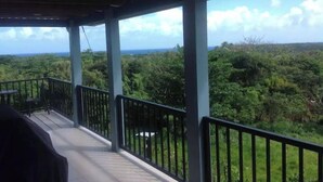A covered outdoor area with a view of dense greenery and the ocean. - Tropical Paradise. Little Corn Island (RAAS)