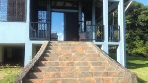 A staircase leading to a covered porch with stone steps and metal railings. - Tropical Paradise. Little Corn Island (RAAS)