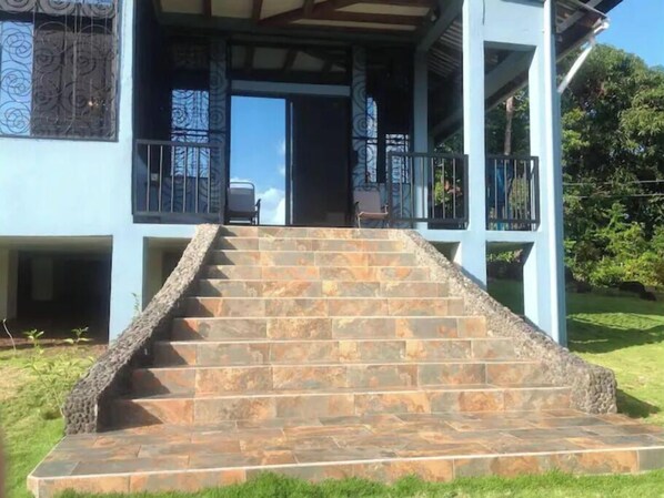 A staircase leading to a covered porch with stone steps and metal railings.