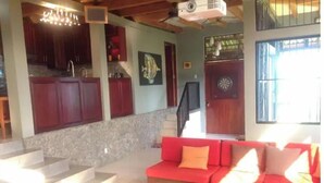 A spacious living area with a red sofa, a coffee table, and a staircase leading to a balcony. - Tropical Paradise. Little Corn Island (RAAS)