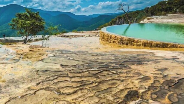 A terraced pool with clear water, surrounded by rocky terrain and mountains in the background. - Spacious Condo With King Size Bed And Skyline Views Of Oaxaca! (Oaxaca de Juárez)