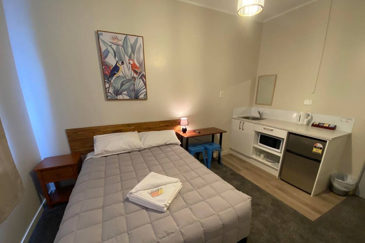 Une chambre d’hôtel comprenant un lit, un bureau, une petite kitchenette et une salle de bain.