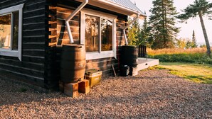Une cabane en rondins avec un toit en métal, une cheminée et une allée gravillonnée.