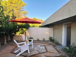 Relax in the serene backyard patio, complete with a comfortable seating area and a shaded table.
