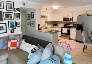 Relax in this stylish living room with a sofa and adjacent kitchen featuring modern appliances and clean cabinetry.