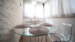 Un comedor moderno con una mesa de vidrio, sillas transparentes y una pared de ladrillo.
