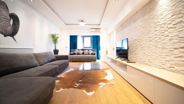 Una sala de estar moderna con un sofá, una mesa de centro, un televisor y una pared de piedra.