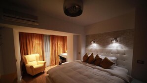 Un dormitorio con una cama grande, una silla, un escritorio y una lámpara fijada a la pared.