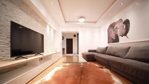 Una sala moderna con un televisor de pantalla plana grande montado en una pared texturizada, un sofá de cuero y un tapiz de piel de vaca.