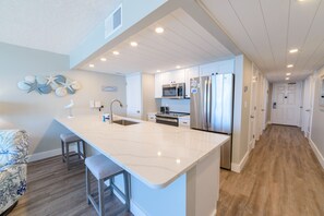 Enjoy cooking in this well-equipped kitchen with a central island, sink, and stools.