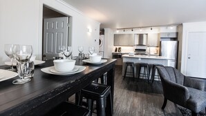Una cocina moderna con encimera oscura, electrodomésticos blancos y una zona de bar con taburetes.
