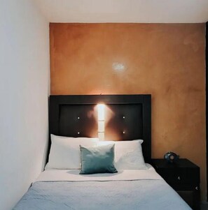 Cozy retreat with a single bed, nightstand, and warm-toned wall.