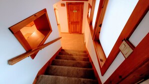 Una escalera con barandas de madera y una ventana pequeña a la izquierda.