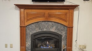 Una chimenea con un televisor encima, un cartel sobre la chimenea y una mesa al frente.