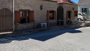 A brick building with a red roof, a gated entrance, and a parked vehicle in the background.