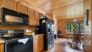 A wooden cabin kitchen with a black stove, microwave, and refrigerator. - Dog Friendly, Fully Gated, Private Cabin by Fool Hollow Lake (Show Low)