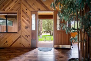 A wooden interior with a door leading outside, a window, and a plant.