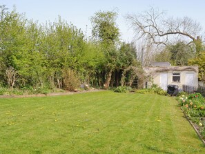 Ein Garten mit einem weißen Haus, einer Rasenfläche und verschiedenen Pflanzen.