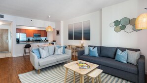 Un salon moderne avec un canapé gris, une table basse en bois et un tapis à rayures.