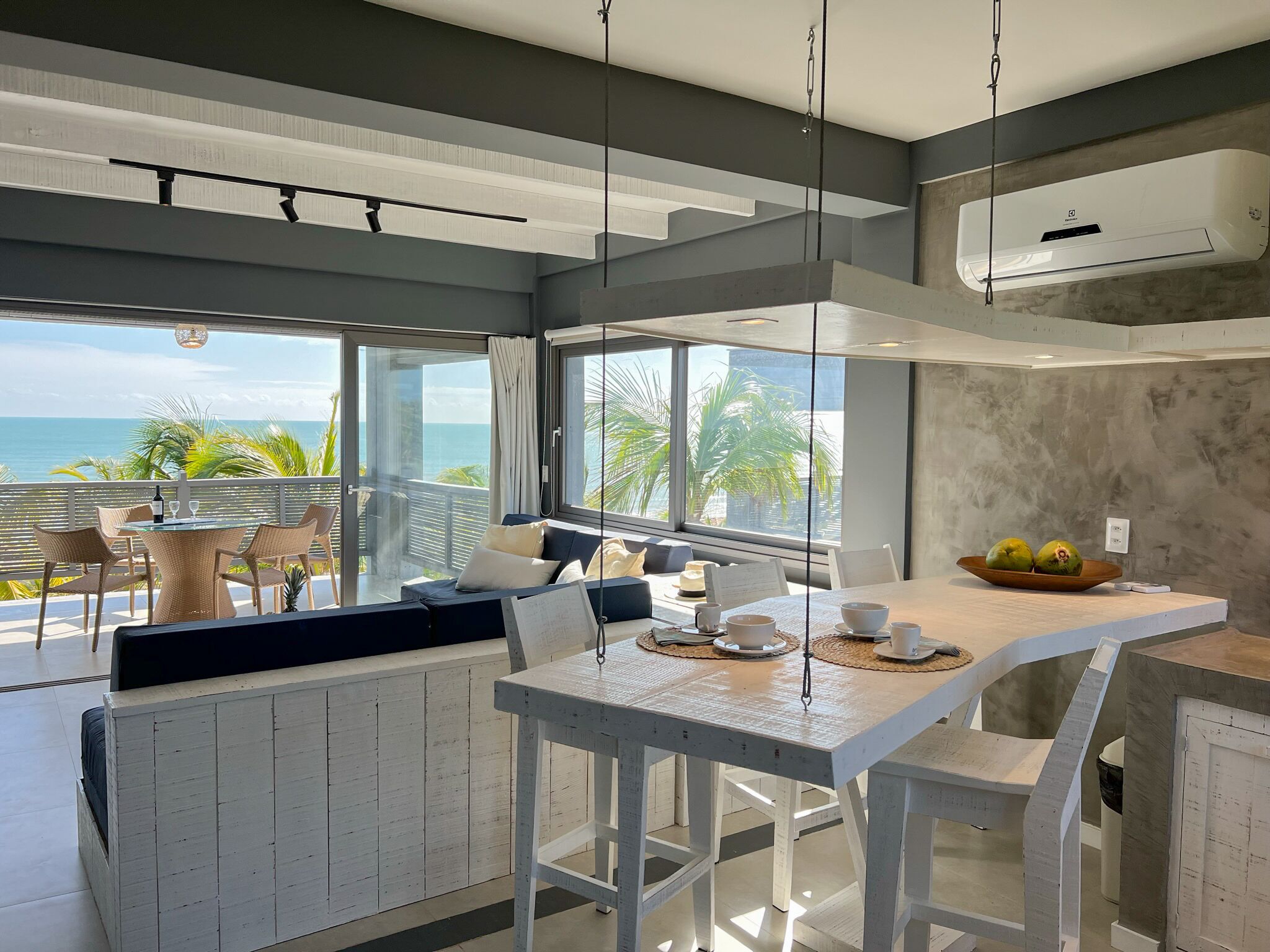 Una cocina moderna con una isla grande, armarios blancos y vista al océano.