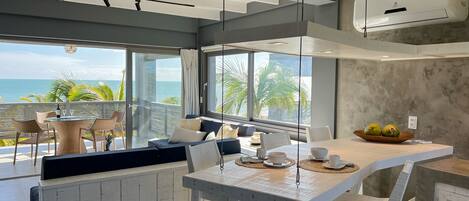 Una cocina moderna con una isla grande, armarios blancos y vista al océano.