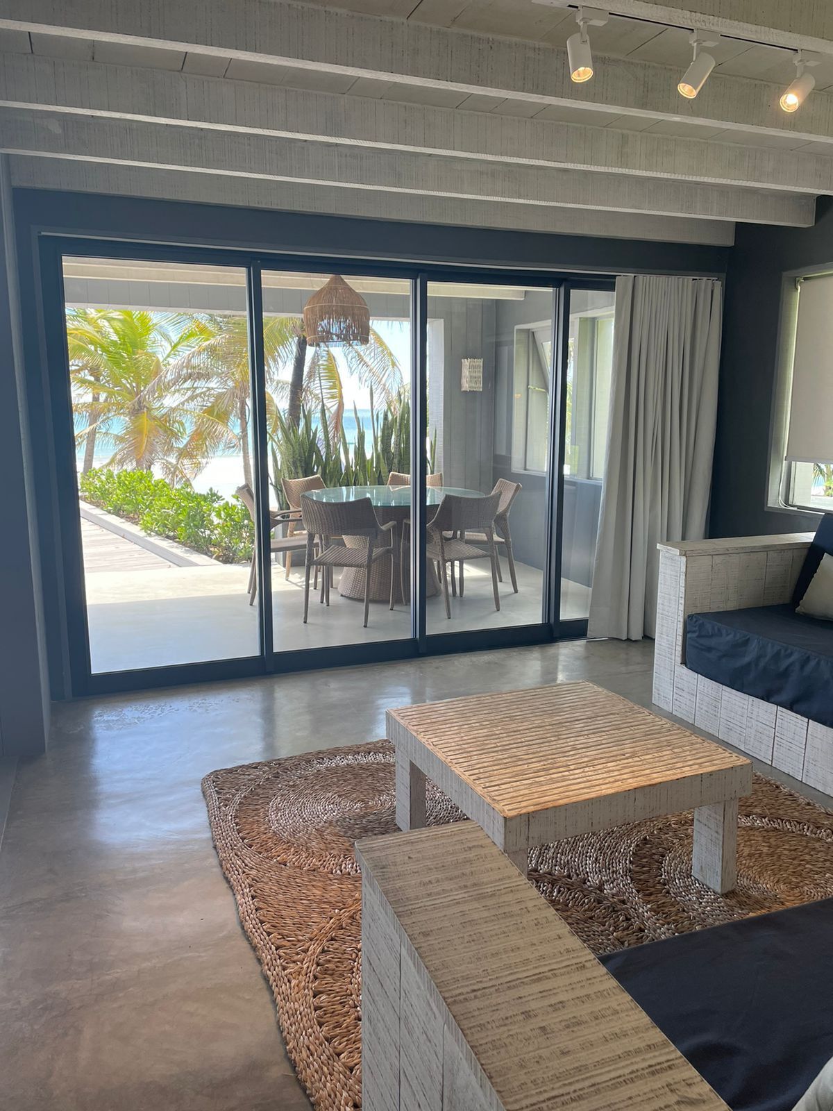 A modern living room with a glass door leading to a balcony, a wooden coffee table, and a sofa.