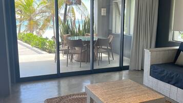A modern living room with a glass door leading to a balcony, a wooden coffee table, and a sofa.