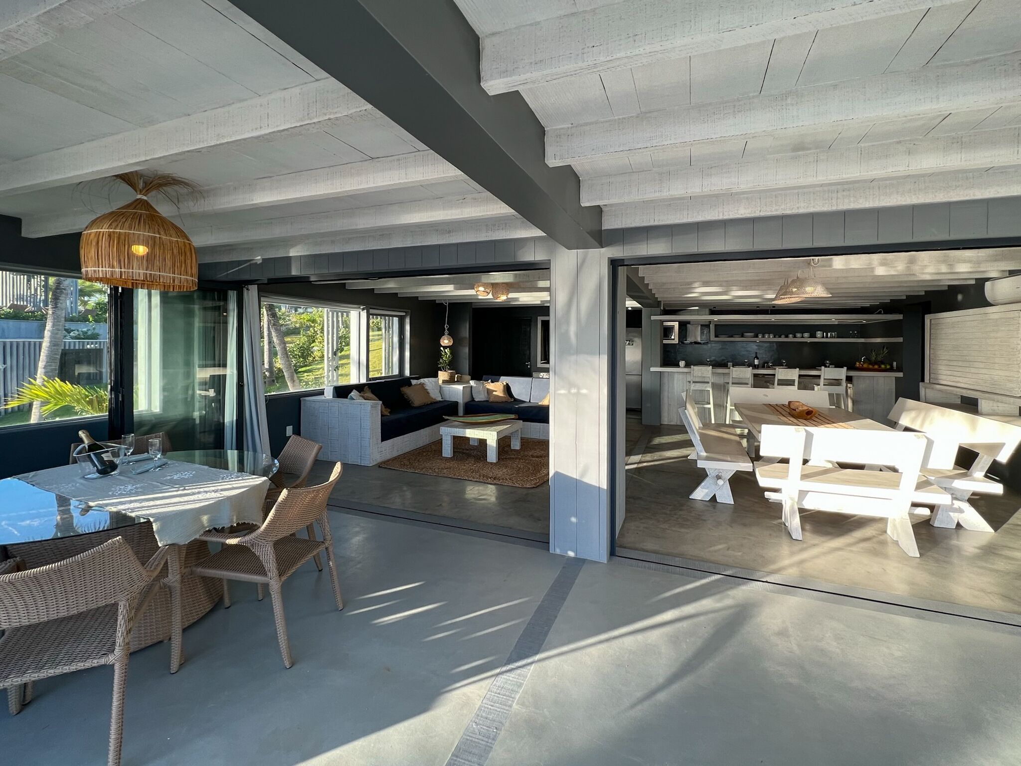 Een moderne, open woonkamer met een eettafel, rieten stoelen en een bank.