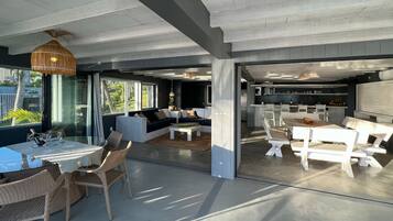 Een moderne, open woonkamer met een eettafel, rieten stoelen en een bank.