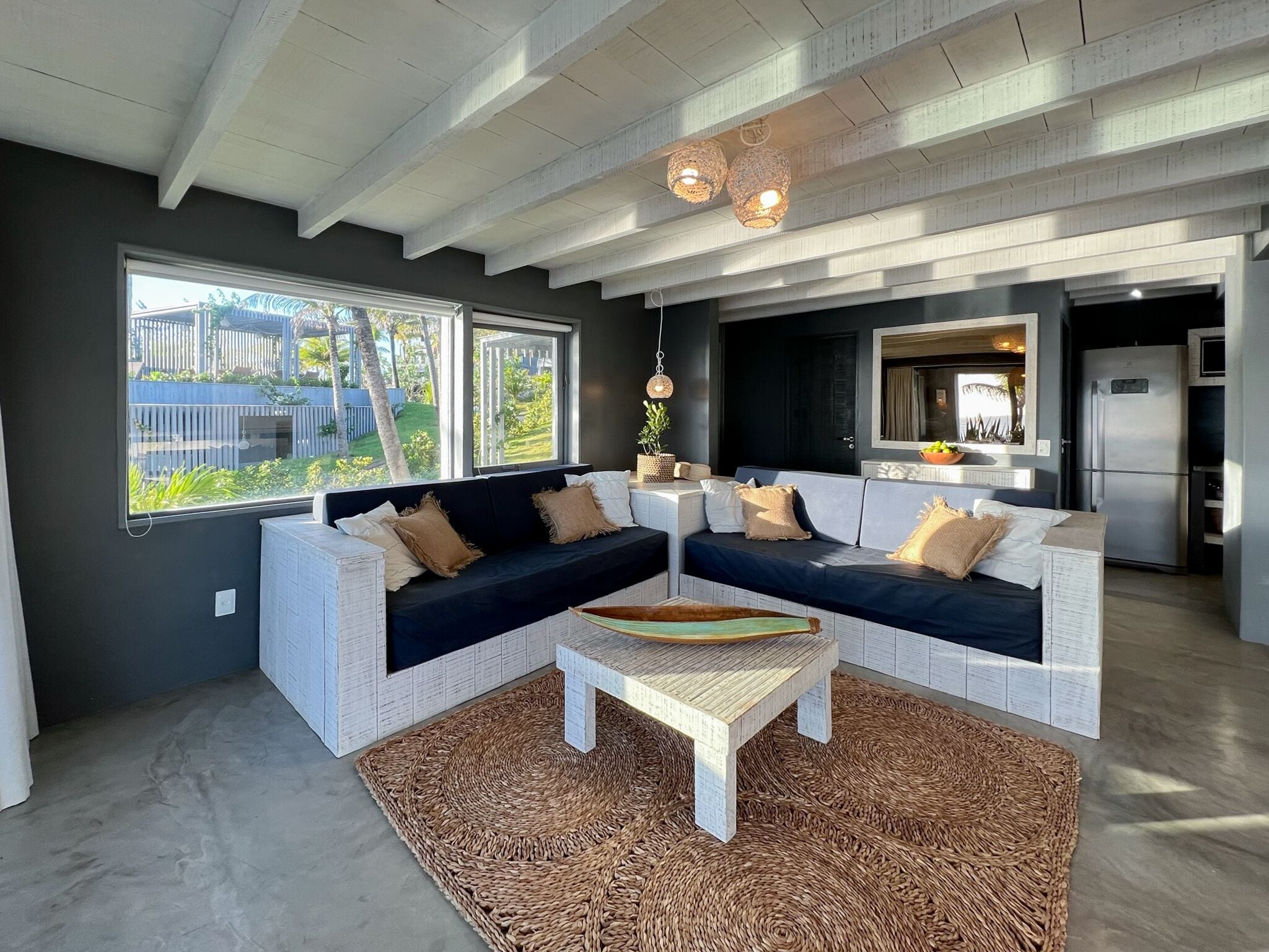 A modern living room with a sectional sofa, a coffee table, and a large window offering a view of the outdoors.