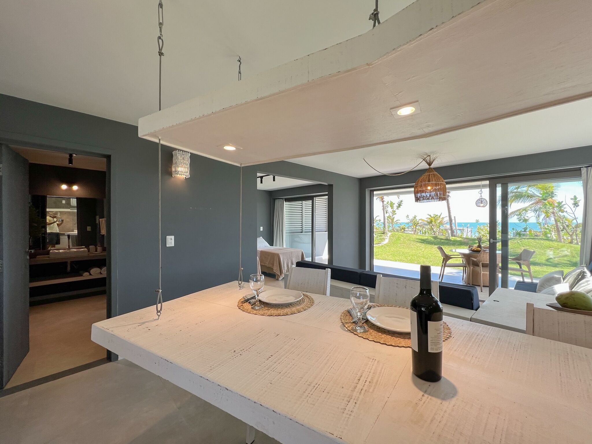 A modern kitchen with a large island, a wine bottle, and a view of the outdoors.