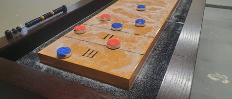Uma mesa de futebol de botão com estrutura de madeira e superfície de jogo escura e texturizada.