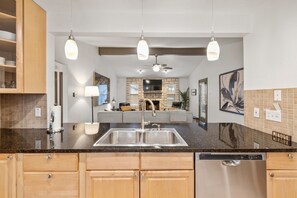 A modern kitchen with granite countertops, stainless steel appliances, and pendant lighting.