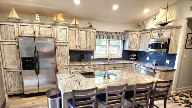 Uma cozinha com ilha central, eletrodomésticos de aço inoxidável e backsplash com azulejos azuis.